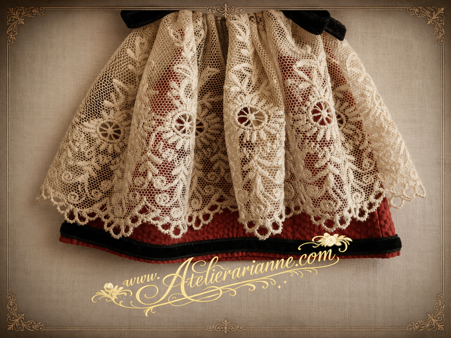 Détail après restauration d’une tenue ancienne de poupée mignonette, montrant la dentelle ancienne brodée sur tulle, la robe rouge et le galon de velours noir.