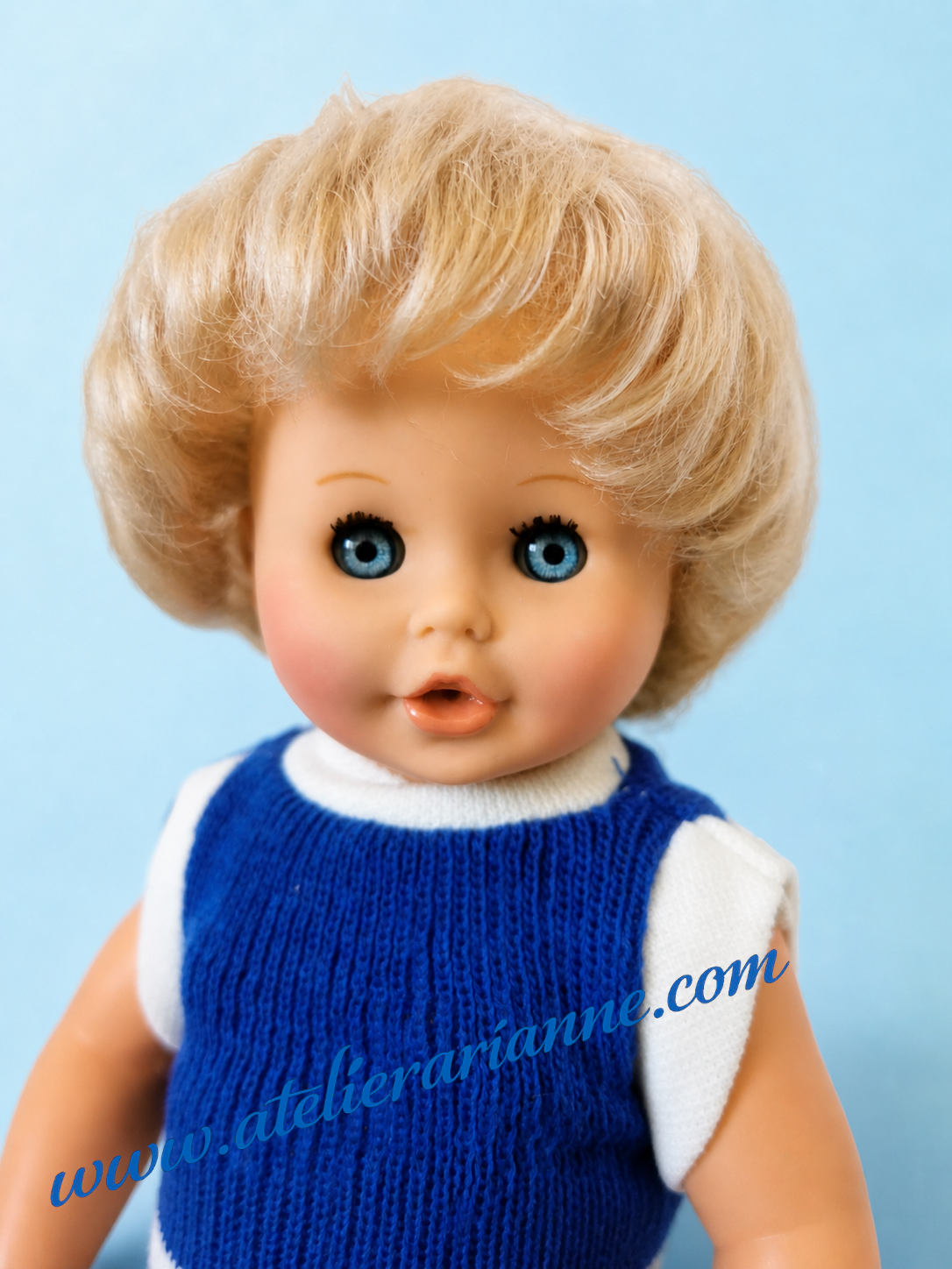 Portrait du poupon Arnaud de Petitcollin apr&egrave;s remise en beaut&eacute;, avec cheveux blonds implant&eacute;s, yeux bleus dormeurs et visage restaur&eacute;.