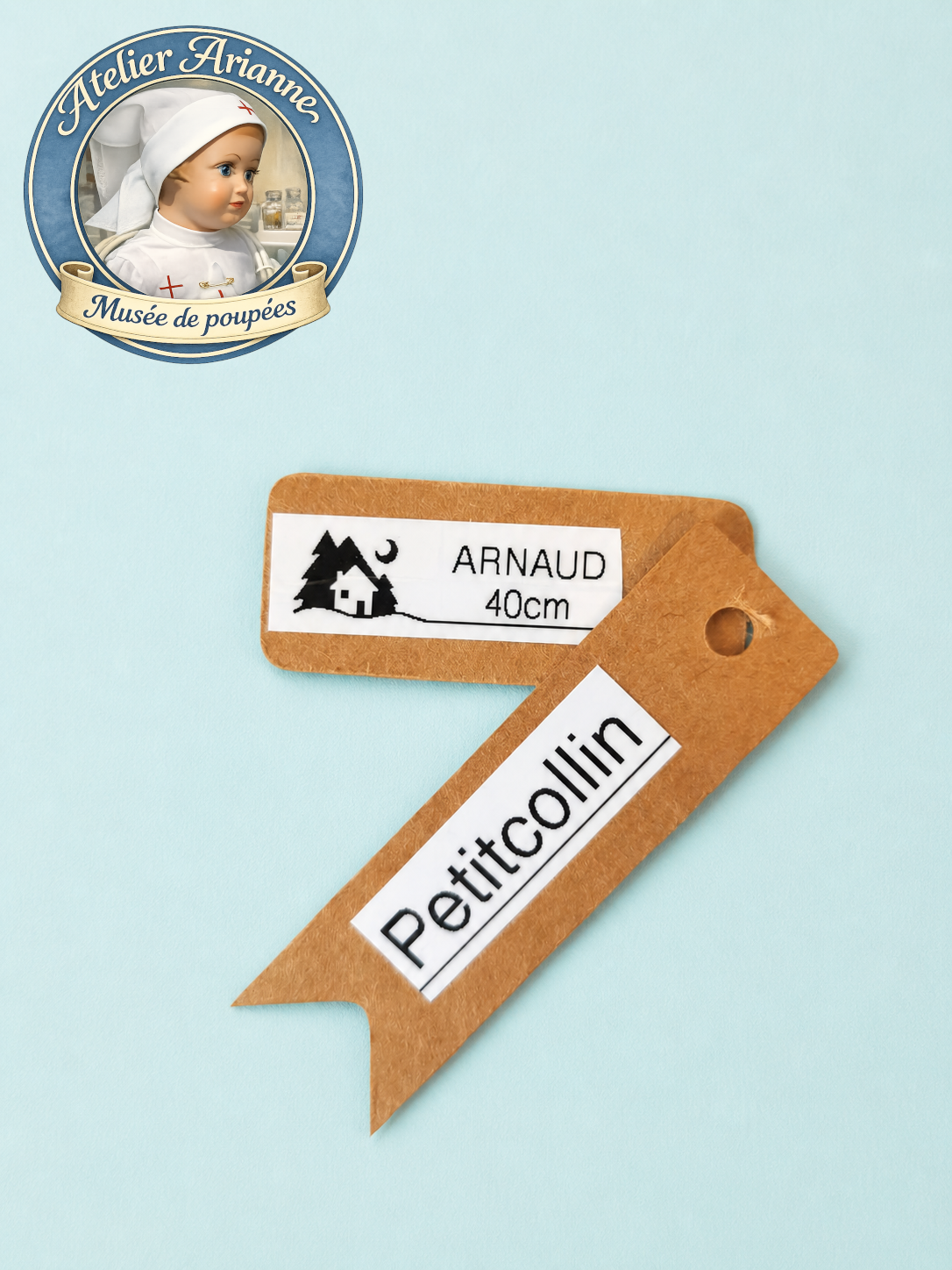 &Eacute;tiquette d&rsquo;identification du poupon Arnaud de Petitcollin, indiquant le nom du mod&egrave;le et la taille 40 cm.