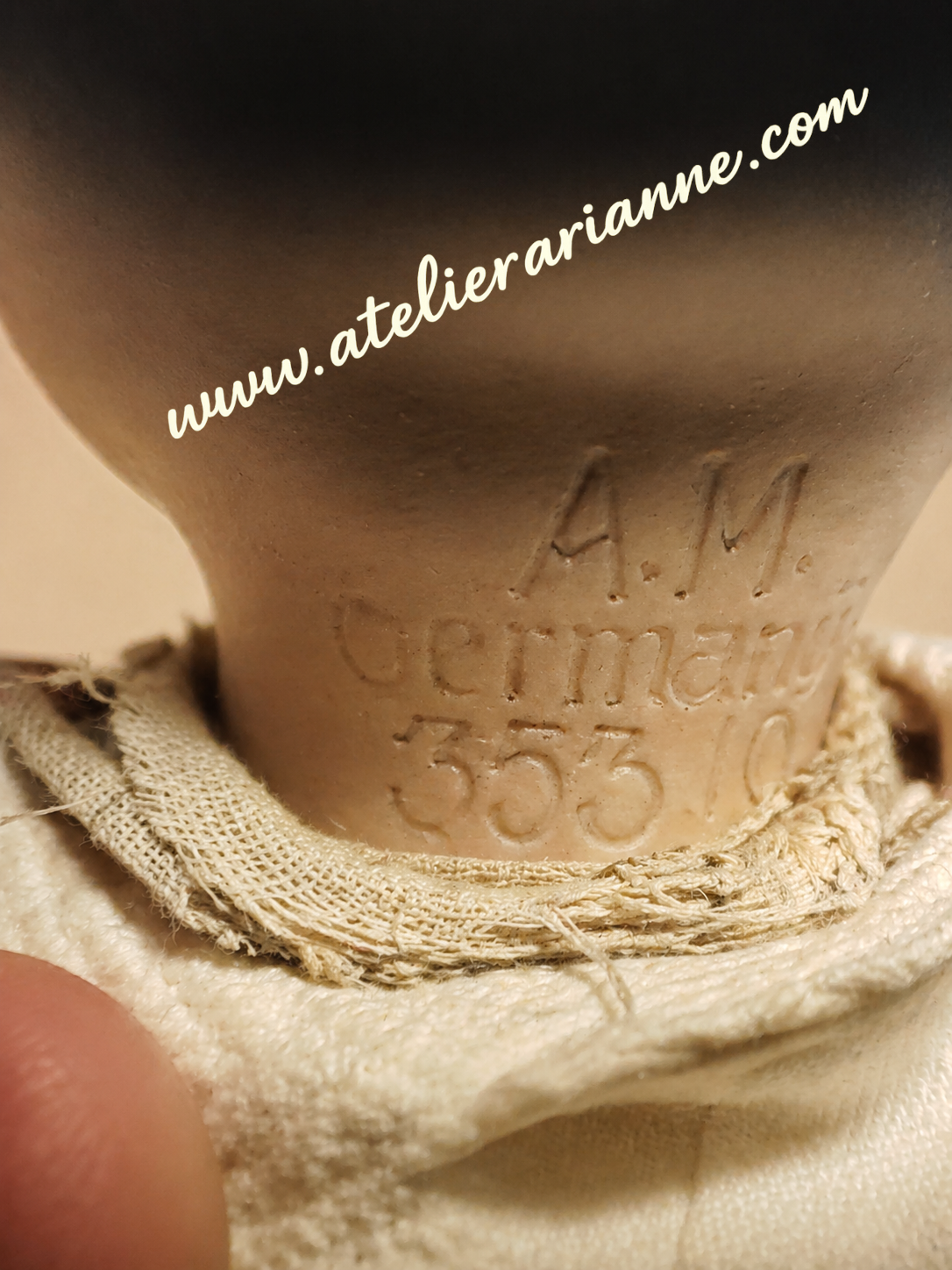 Marquage au dos de la t&ecirc;te : A.M. Germany 353 / 10. Ce marquage identifie une poup&eacute;e de caract&egrave;re Armand Marseille, moule 353, taille 10, de fabrication allemande.