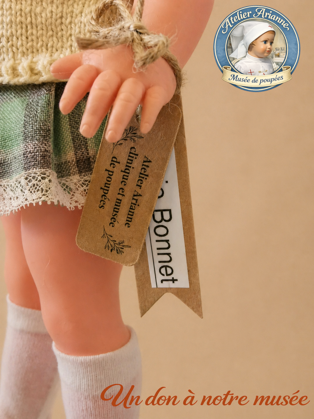 D&eacute;tail de la petite poup&eacute;e Bella restaur&eacute;e pour le mus&eacute;e Atelier Arianne, avec sa main, sa jupe, sa dentelle et son &eacute;tiquette de mus&eacute;e apr&egrave;s remise en pr&eacute;sentation.