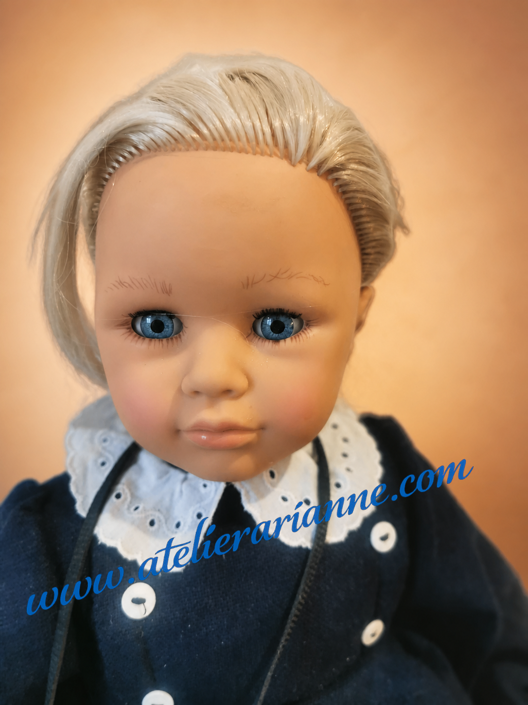 Portrait d&rsquo;une poup&eacute;e italienne Zanini Zambelli donn&eacute;e au mus&eacute;e Atelier Arianne par Dominique, avec grands yeux bleus, robe bleu marine &agrave; col blanc et cheveux blonds.