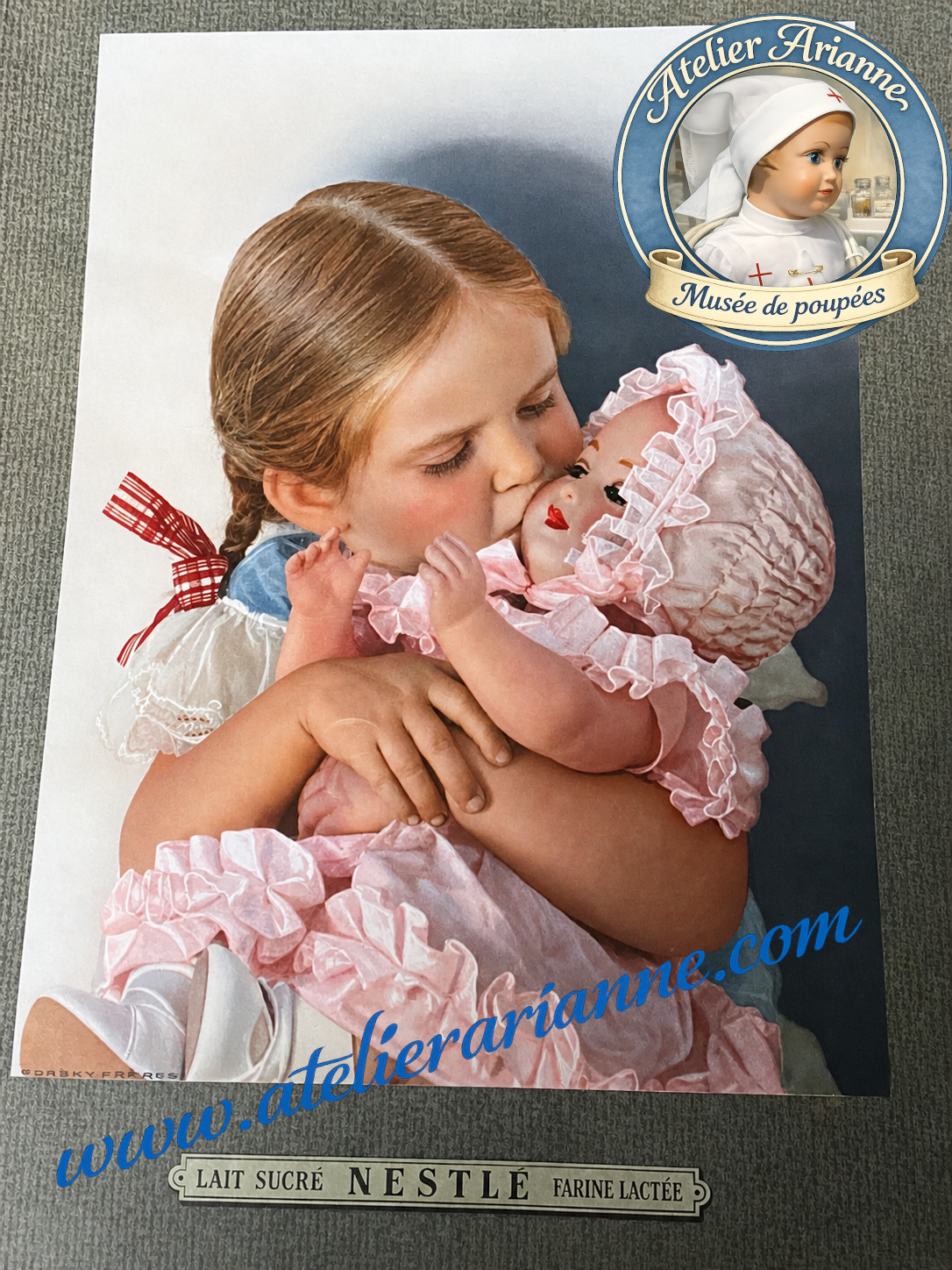 François de SNF, bébé Nestlé ancien en celluloïd, présenté avec sa boîte ronde d’origine et son affiche publicitaire Nestlé ancienne.