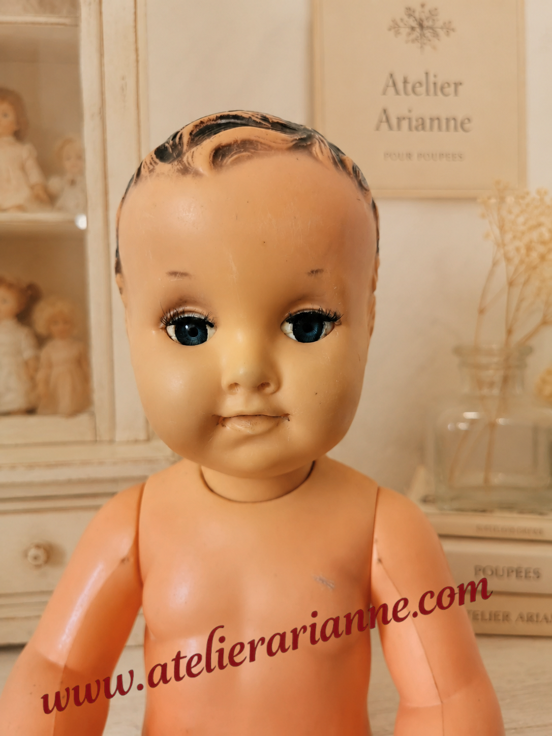 Gros plan du visage d&rsquo;un petit baigneur ancien restaur&eacute; par la clinique de poup&eacute;es Atelier Arianne, avec nouveaux cils et remise en pr&eacute;sentation.