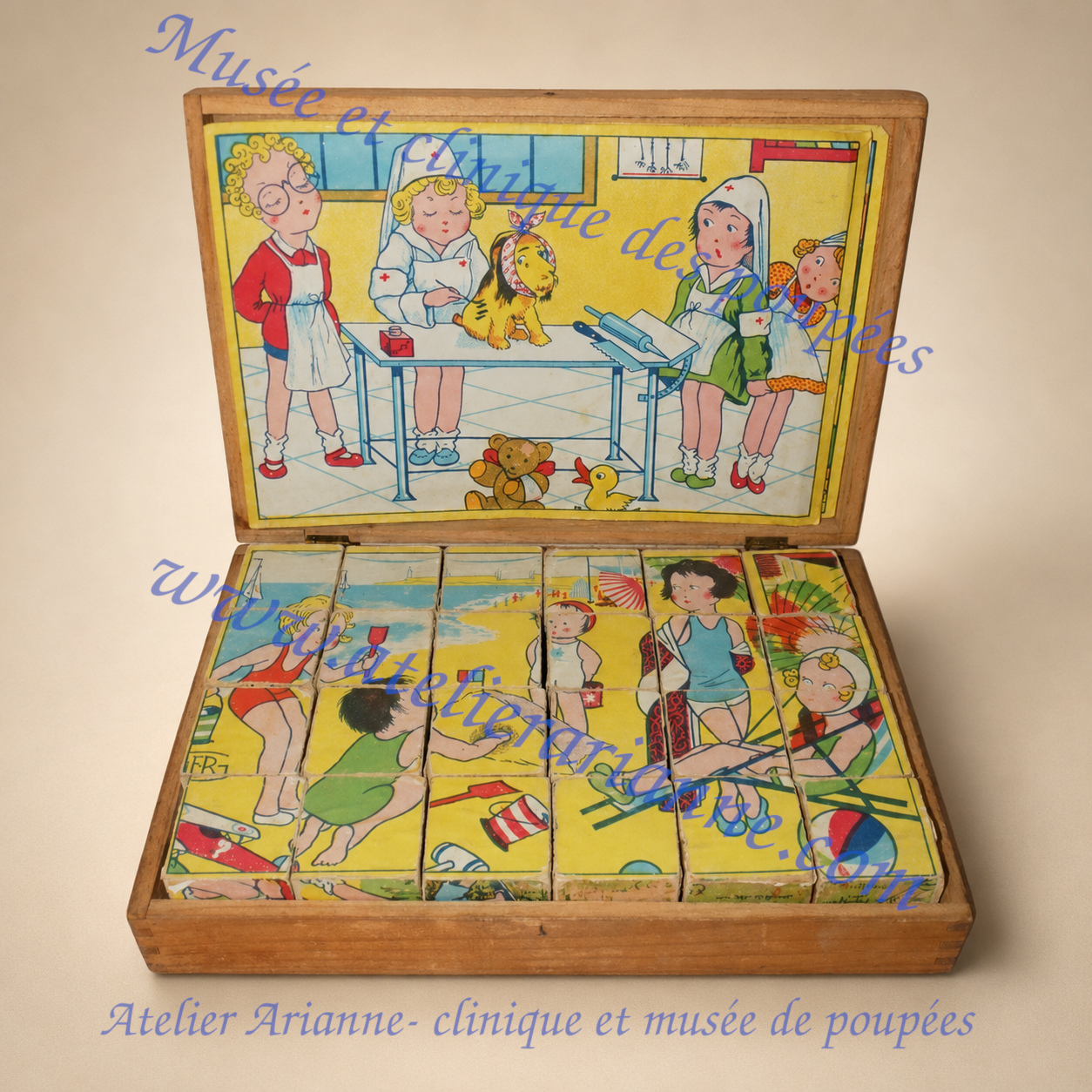 Coffret ouvert d&rsquo;un ancien jeu de cubes en bois pr&eacute;sentant une sc&egrave;ne de clinique sur le couvercle et une autre illustration reconstitu&eacute;e avec les cubes.
